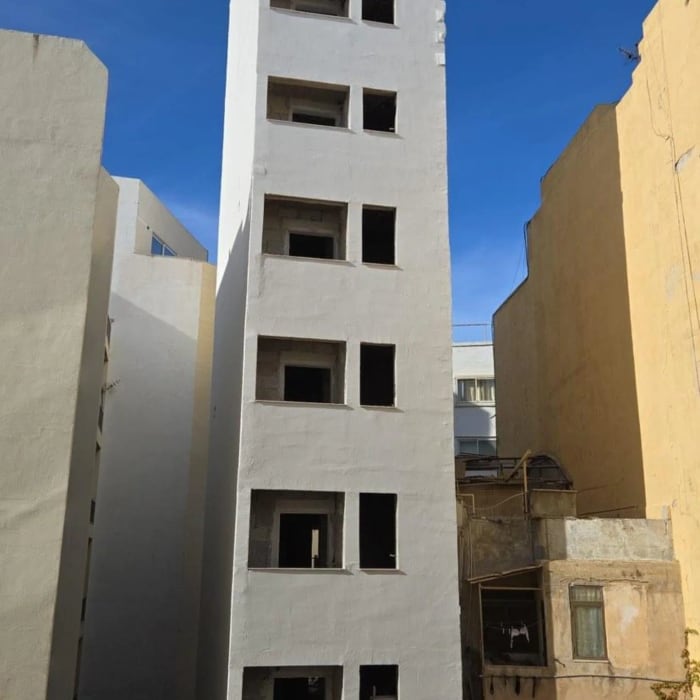 A white apartment block against a blue sky
