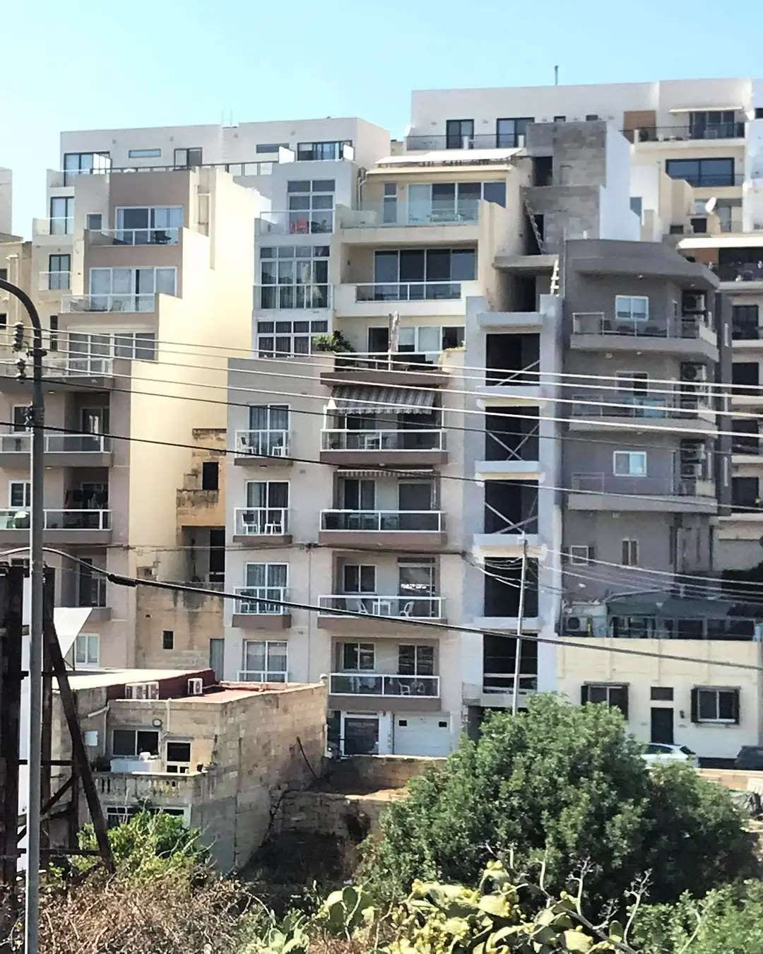 A tall white apartment block bristling with balconies
