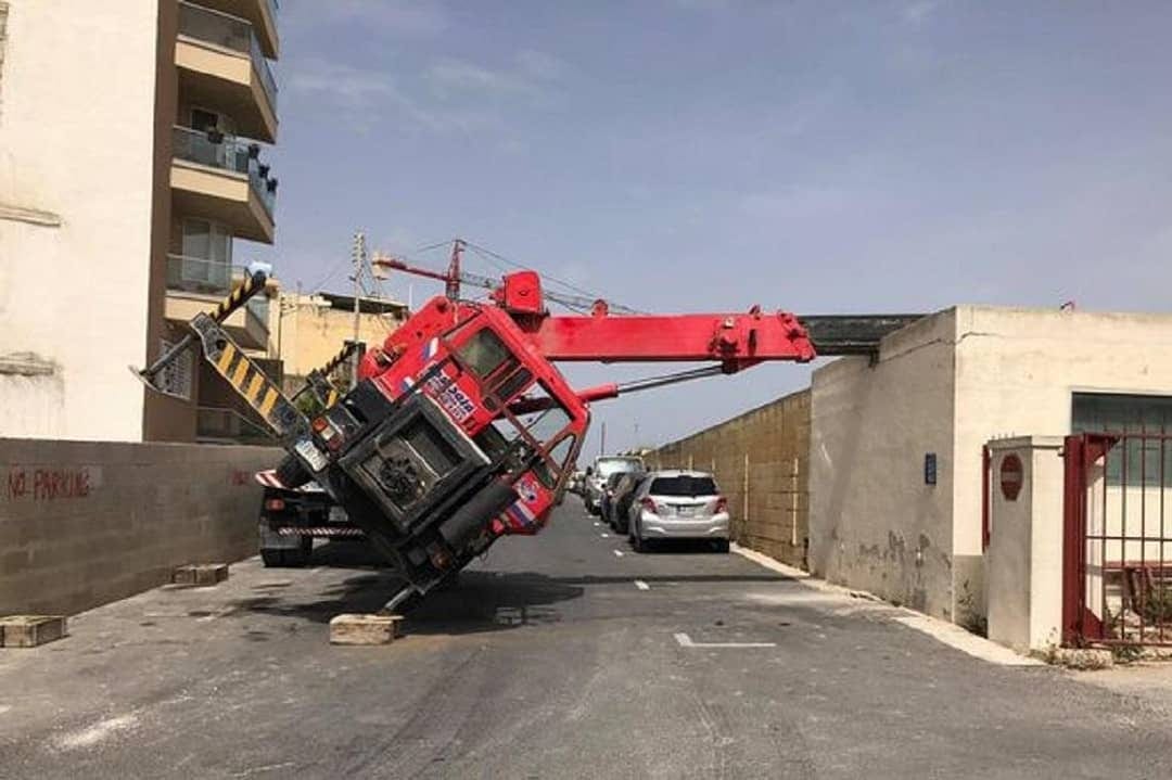 A red lifting crane parked on a street corner