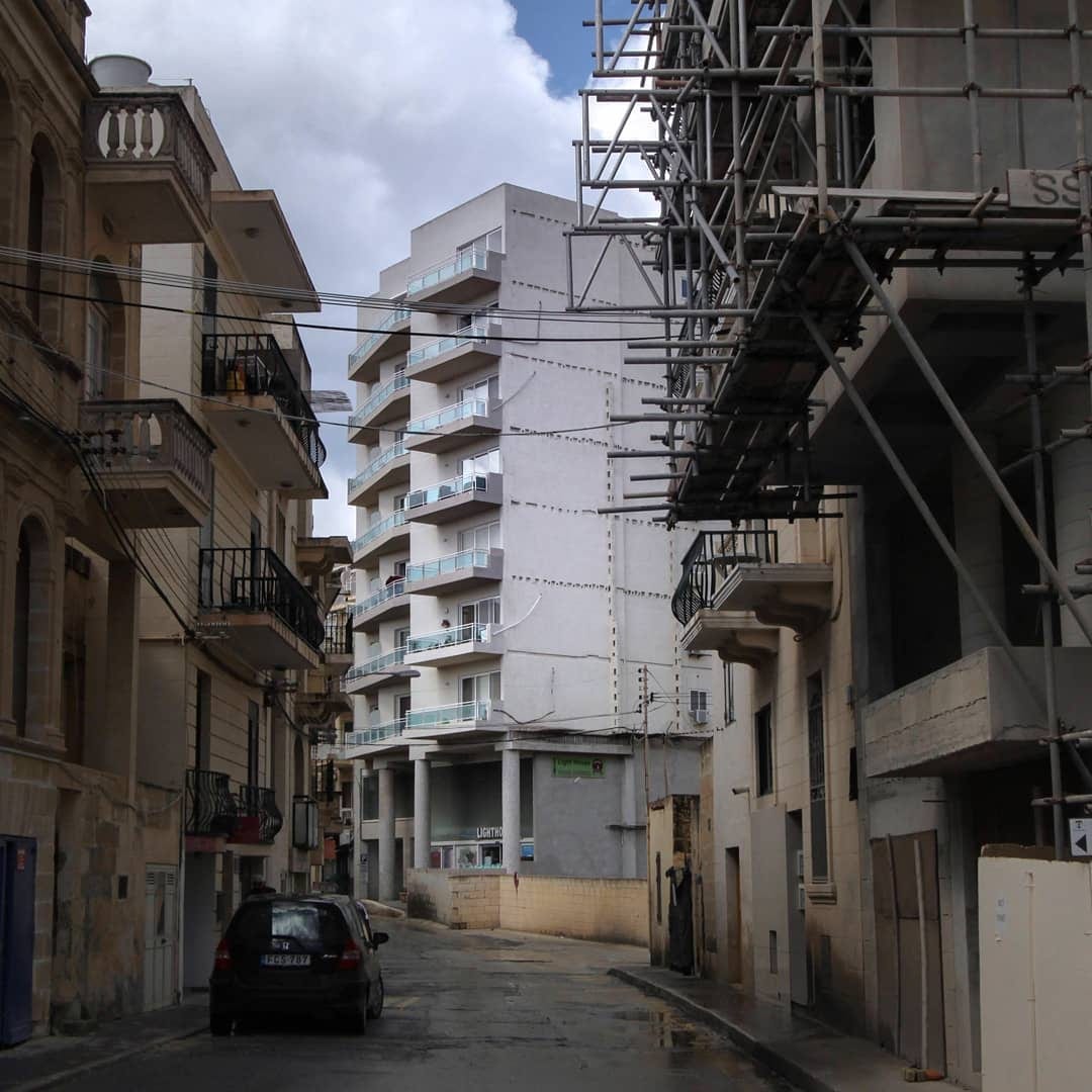 An apartment under scaffolding on a narrow street