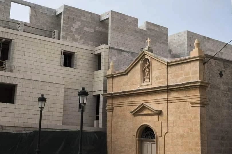 A historic chapel beside a large concrete structure
