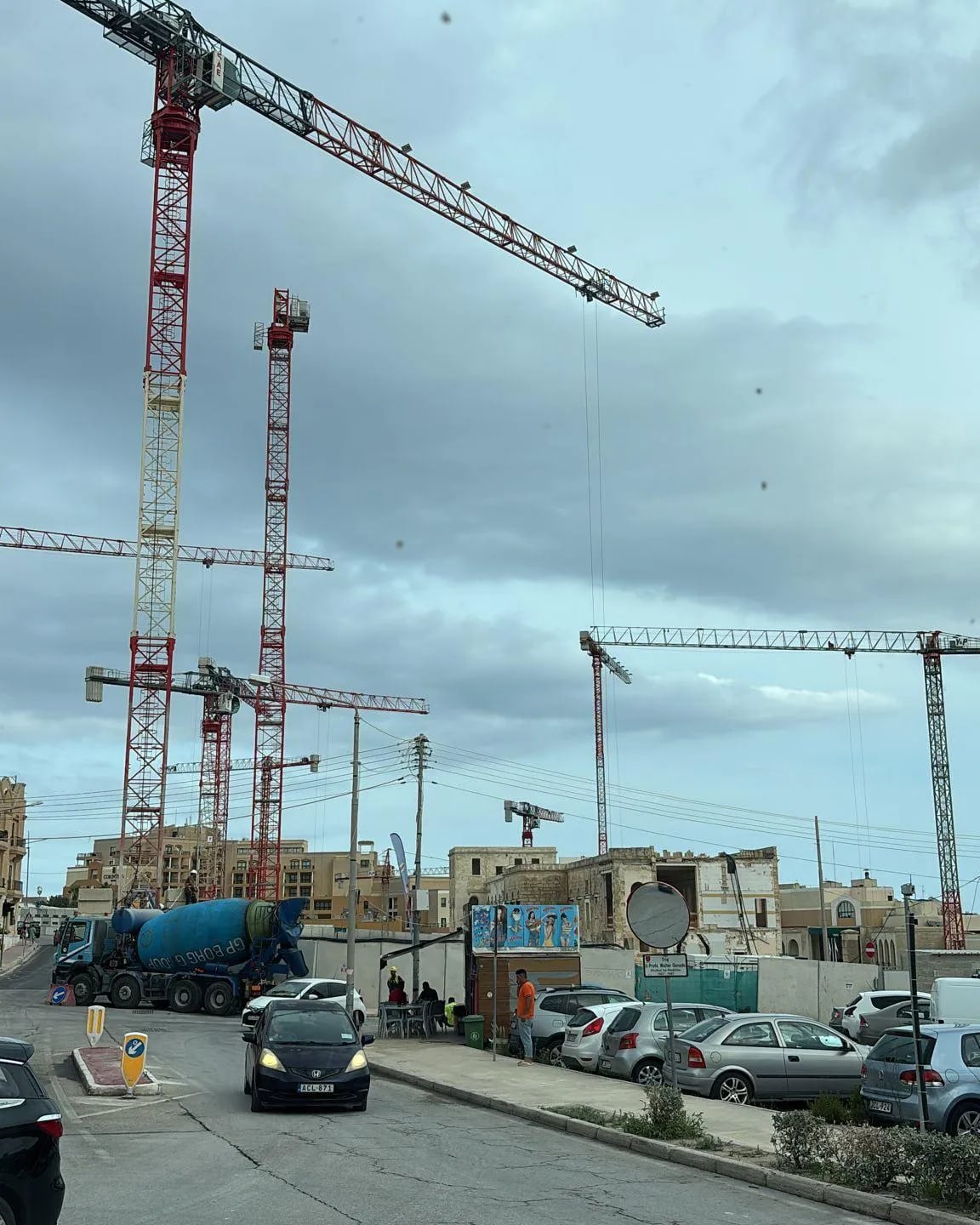 Tower cranes silhouetted against the sky over a building site