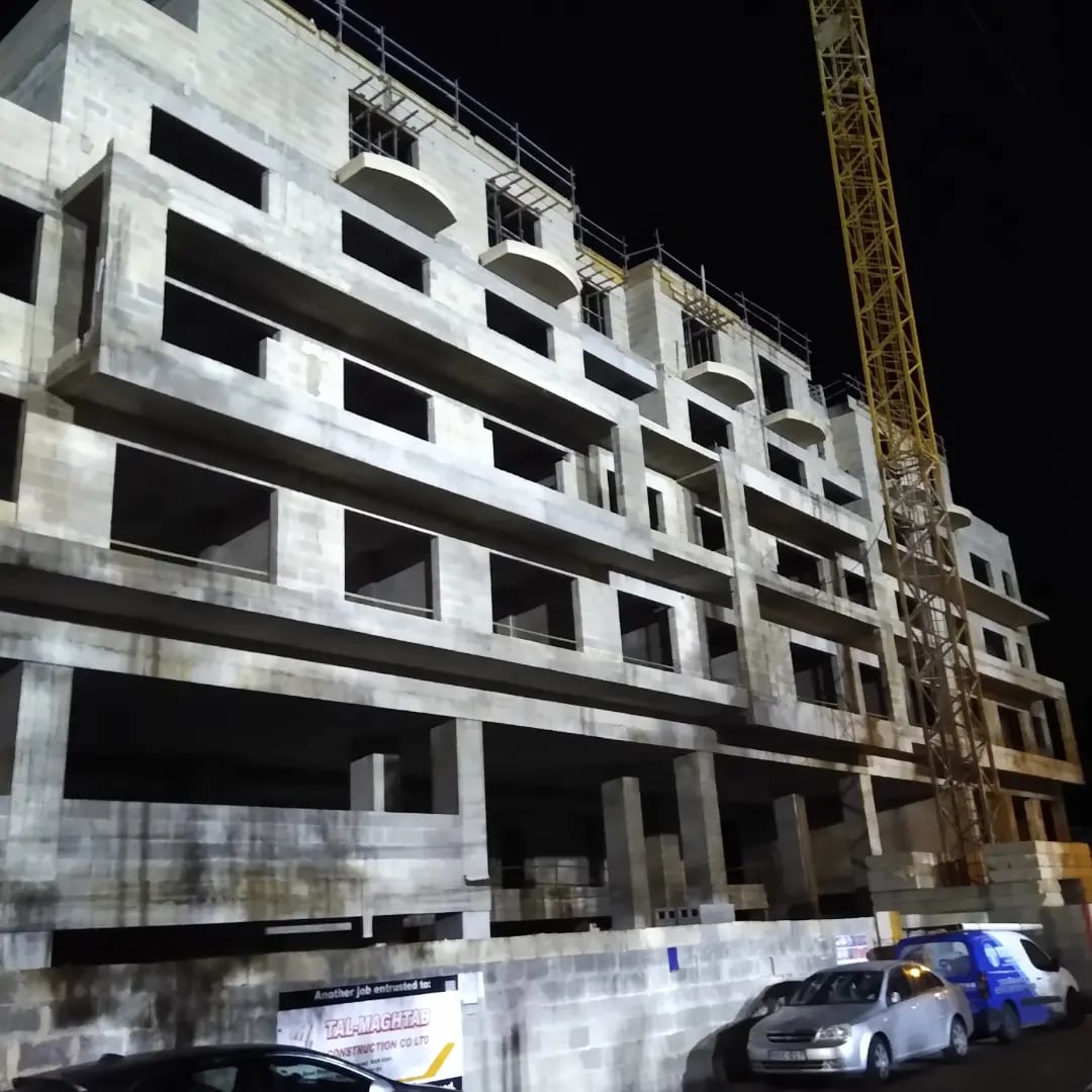 Concrete building skeleton under construction with a crane