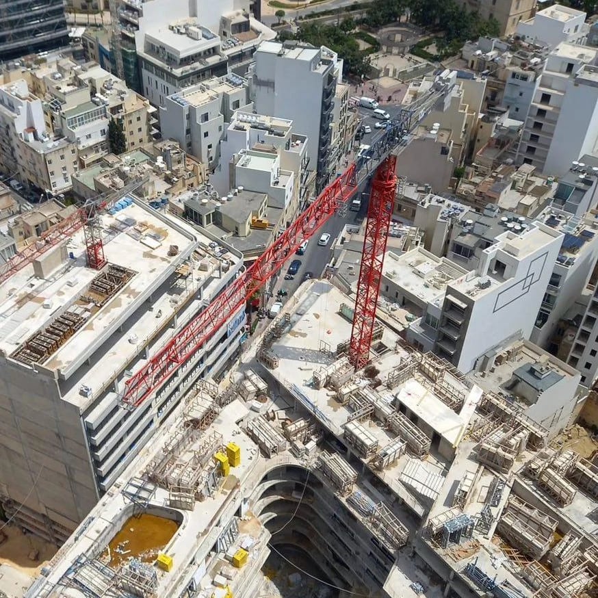 Aerial view of a dense Maltese construction site bristling with tower cranes