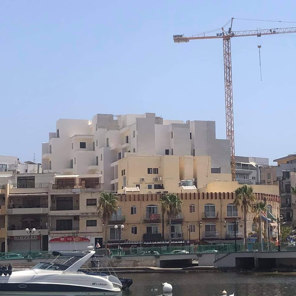 A waterfront skyline of towers and a crane