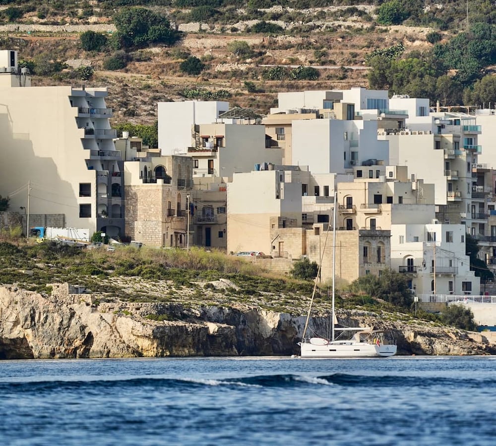 Buildings crowding a clifftop above a bay