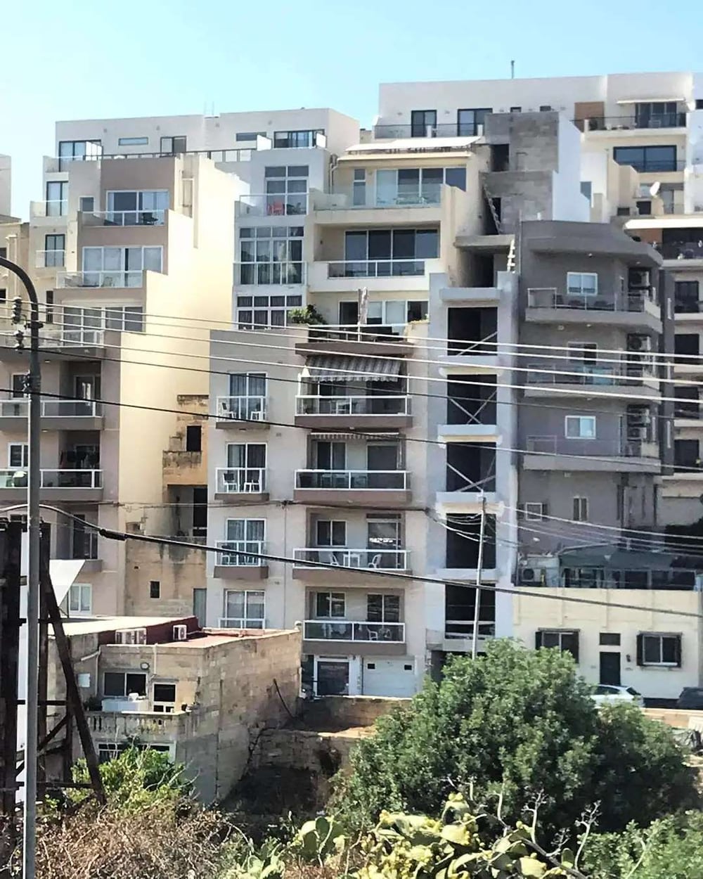 A tall white apartment block bristling with balconies